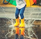 Child jumping in puddle in the rain