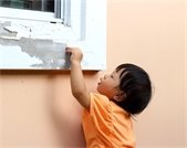 Child chipping paint off a window frame