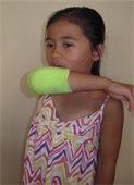 Child coughing into the crook of her arm with a sock over her elbow
