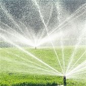 Irrigation sprinklers spraying water over grass.