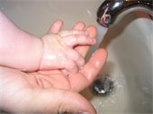 Infant's hands being washed at the sink