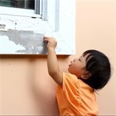 Picture of child peeling chipping paint off a house exterior